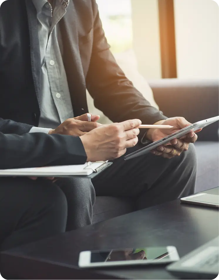 Gros plan de professionnels en réunion discutant de stratégie juridique d'entreprise avec des tablettes et des carnets.