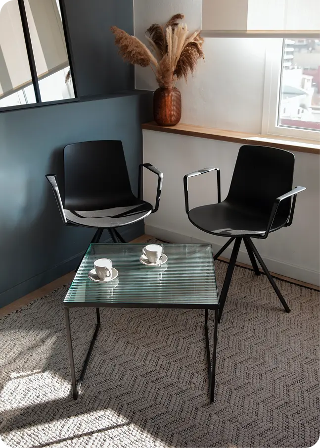 Un espace de réunion moderne et élégant avec deux chaises et une table basse, représentant le cadre de conseil pour la vie de l'entreprise.