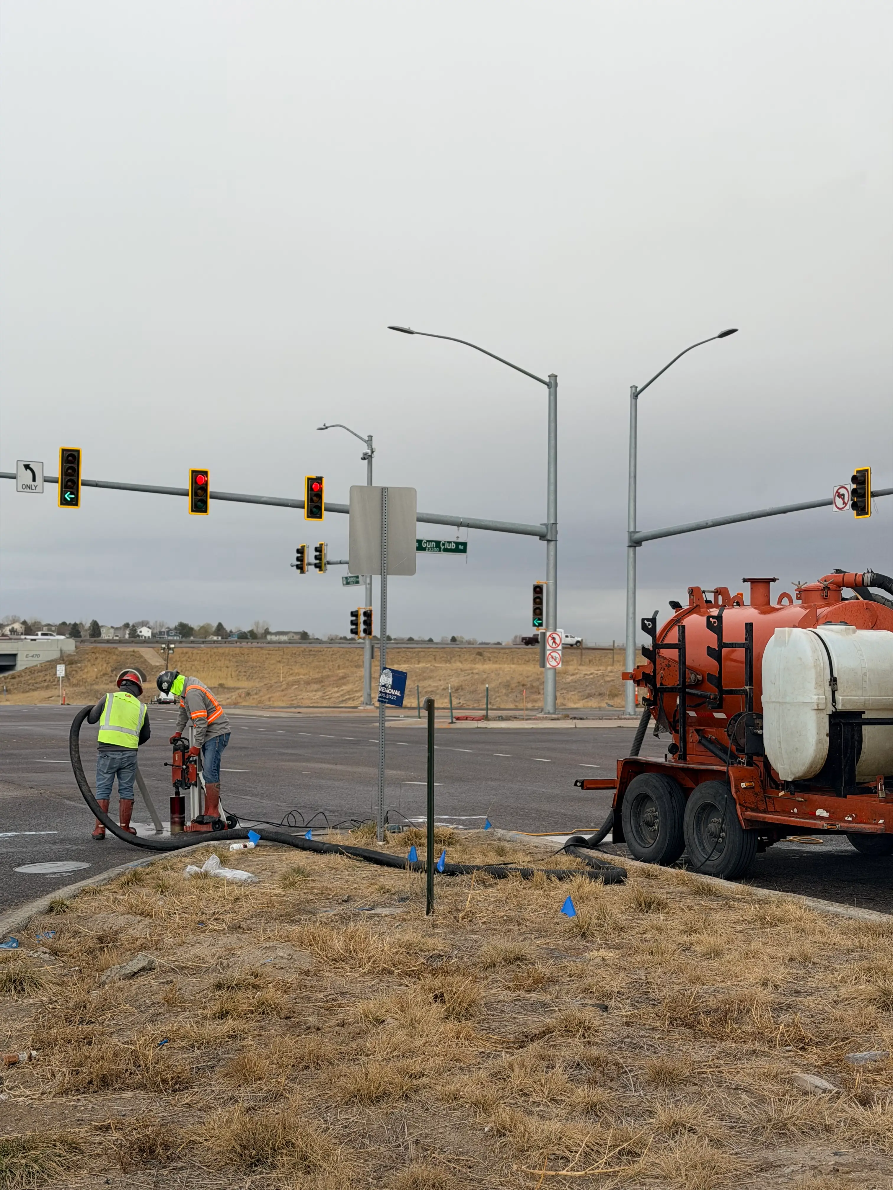Nighttime roadwork scene with workers using machinery and cones blocking off a street near a lit Festival Center sign and a red traffic light.