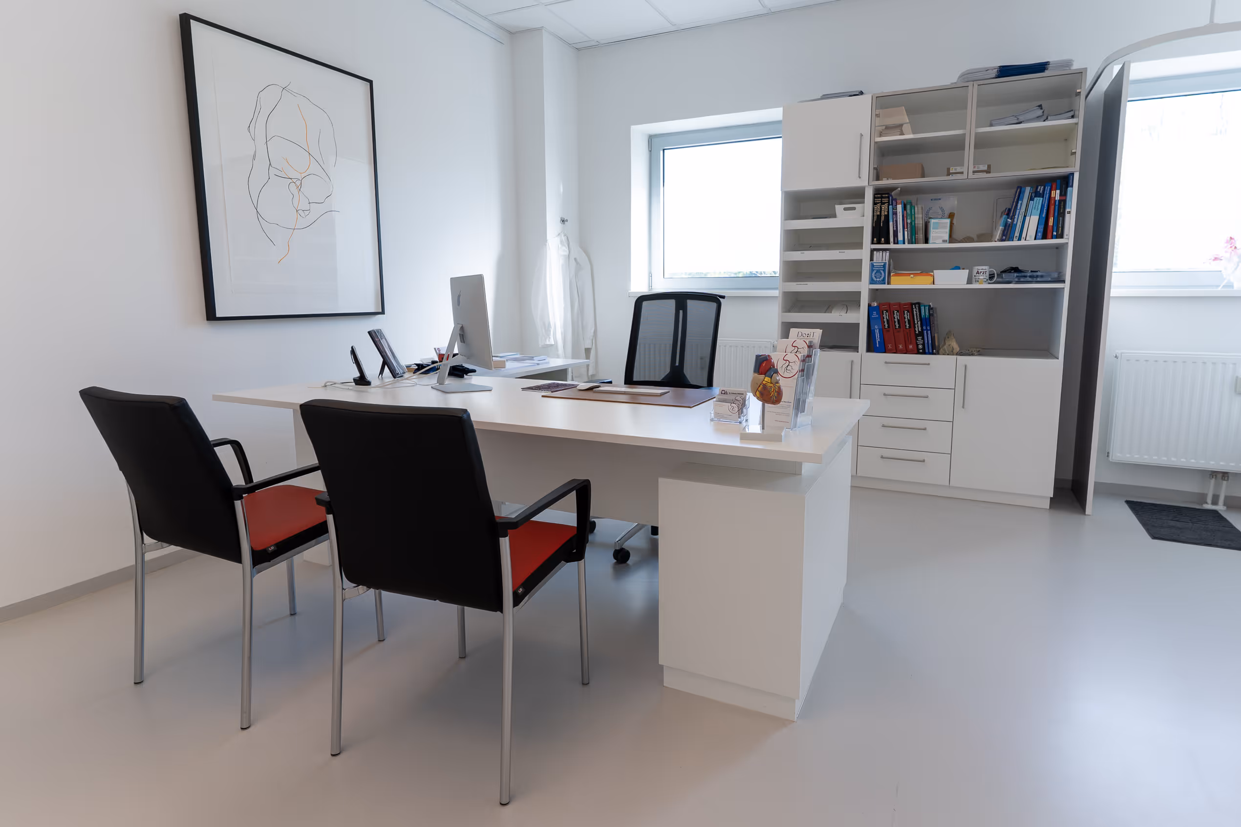 Modern Arztzimmer mit weißem Schreibtisch, zwei Stühlen, Bücherschrank und Wandskizze.