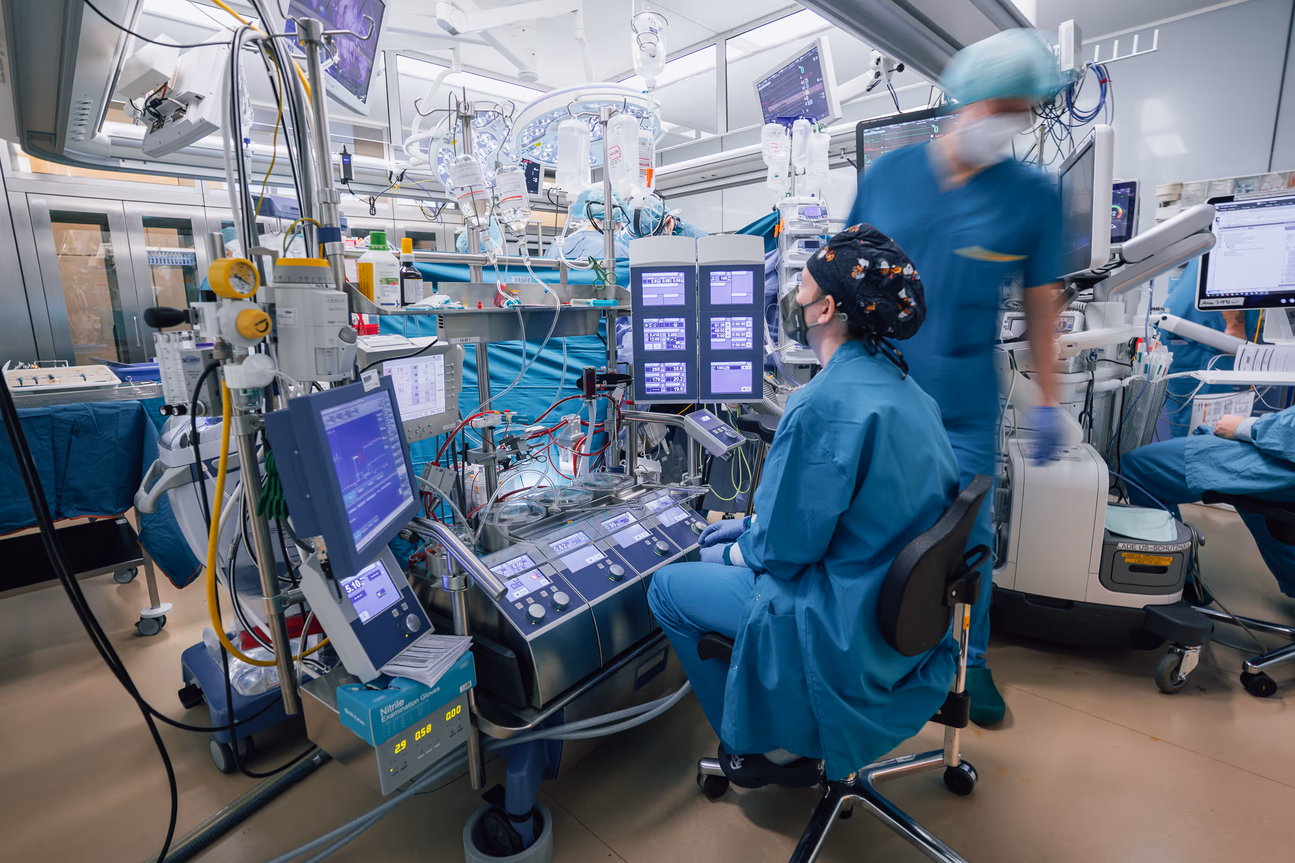 Krankenhaussaal mit medizinischem Personal und Überwachungsgeräten während einer Operation.