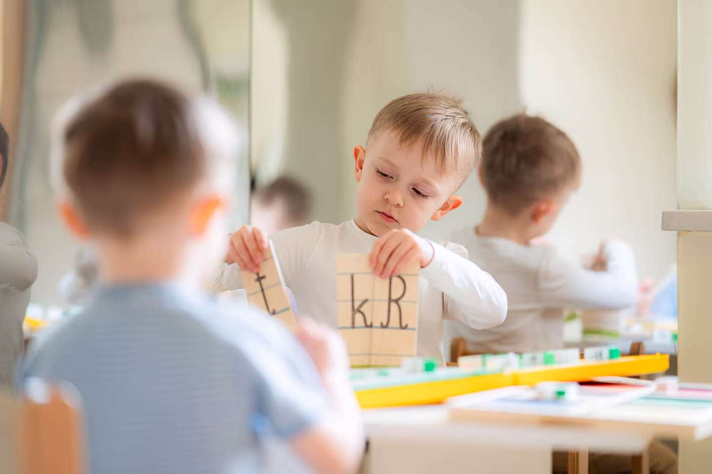Chłopiec układający drewniane klocki z literami przy stoliku w Przedszkolu Zegar Słoneczny