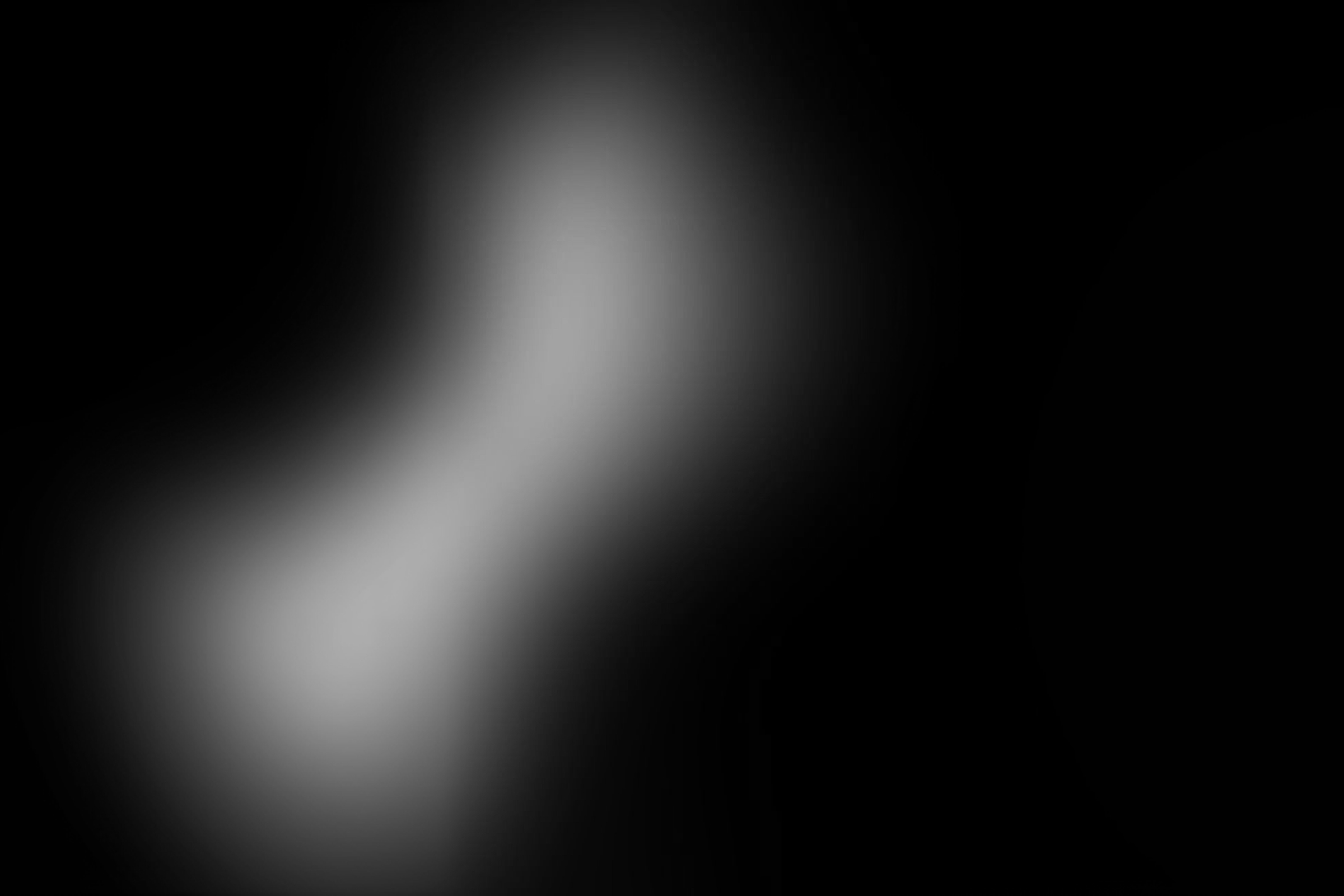 Black background with an abstract soft white light shape in the center.