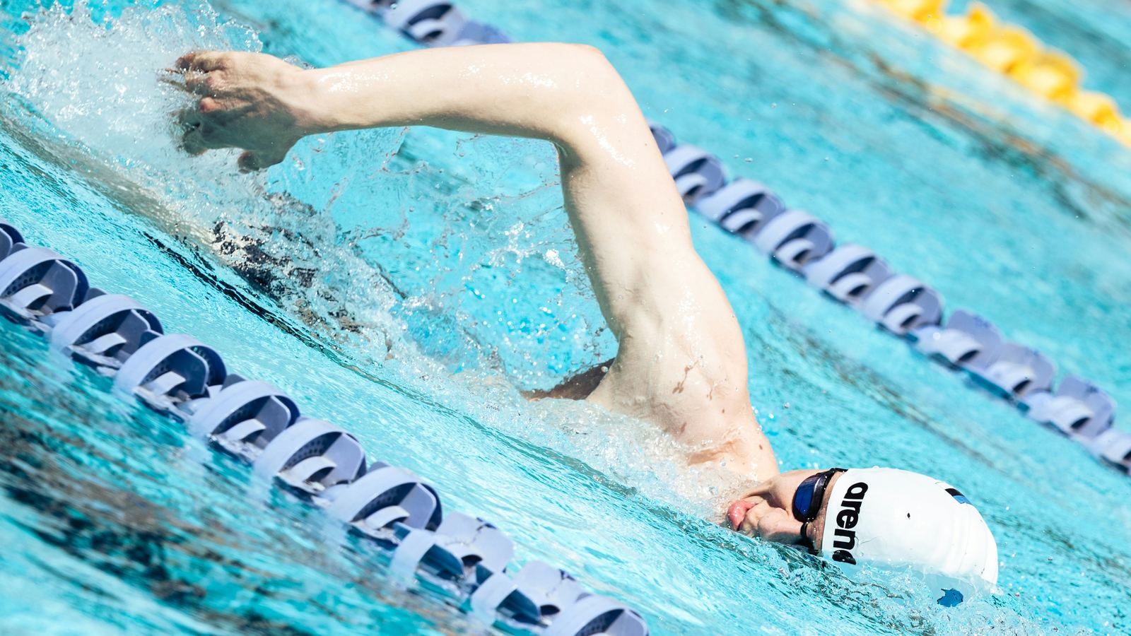A swimmer racing freestyle between lane ropes