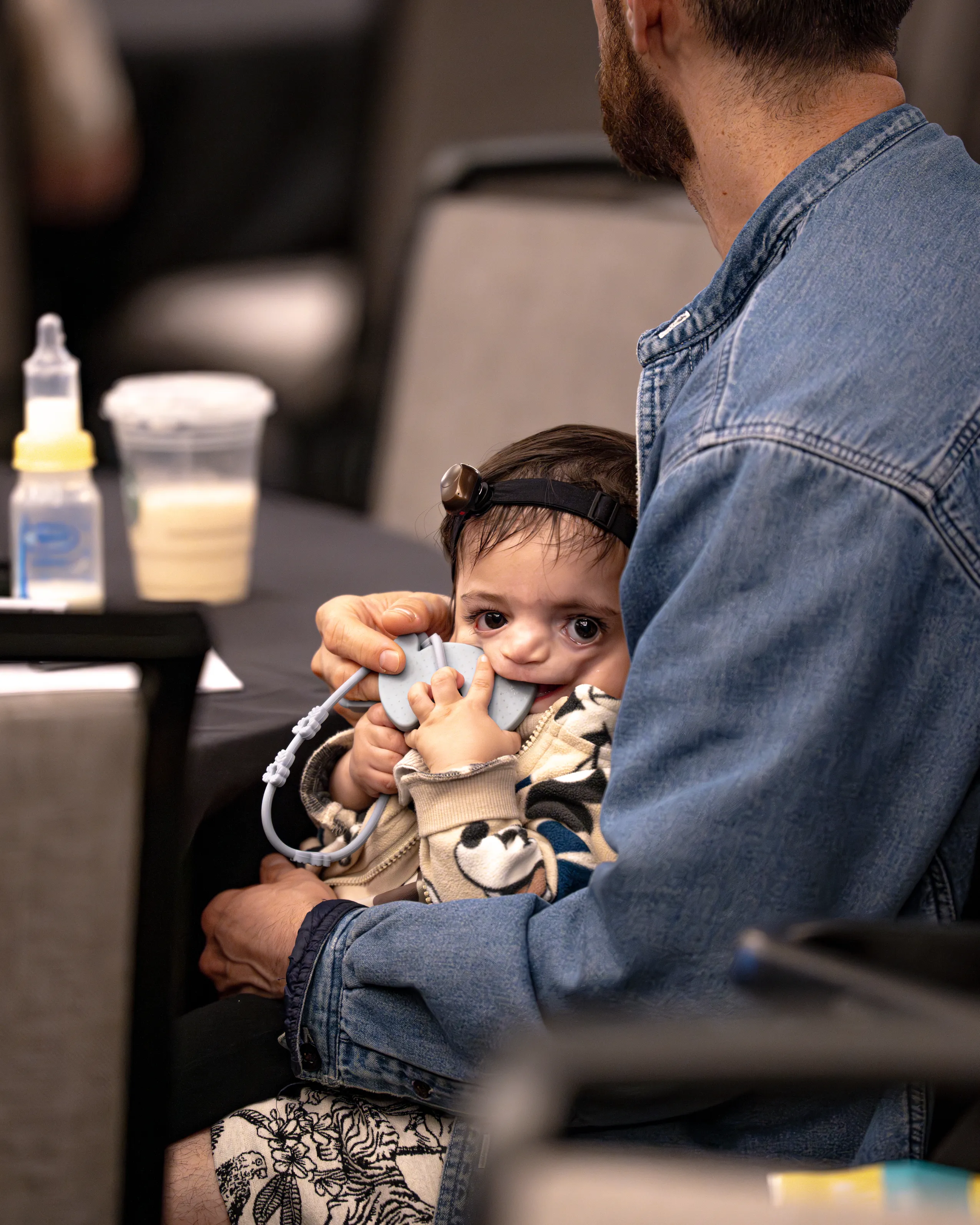 A parent holds a baby while reviewing a syndrome booklet