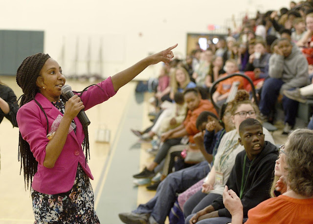 A speaker addresses a seated audience during a peer story event