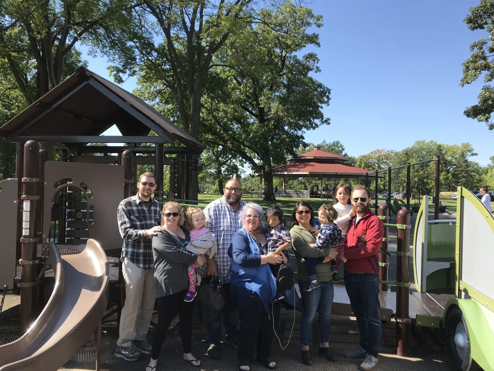 A group poses together near a playground pavilion