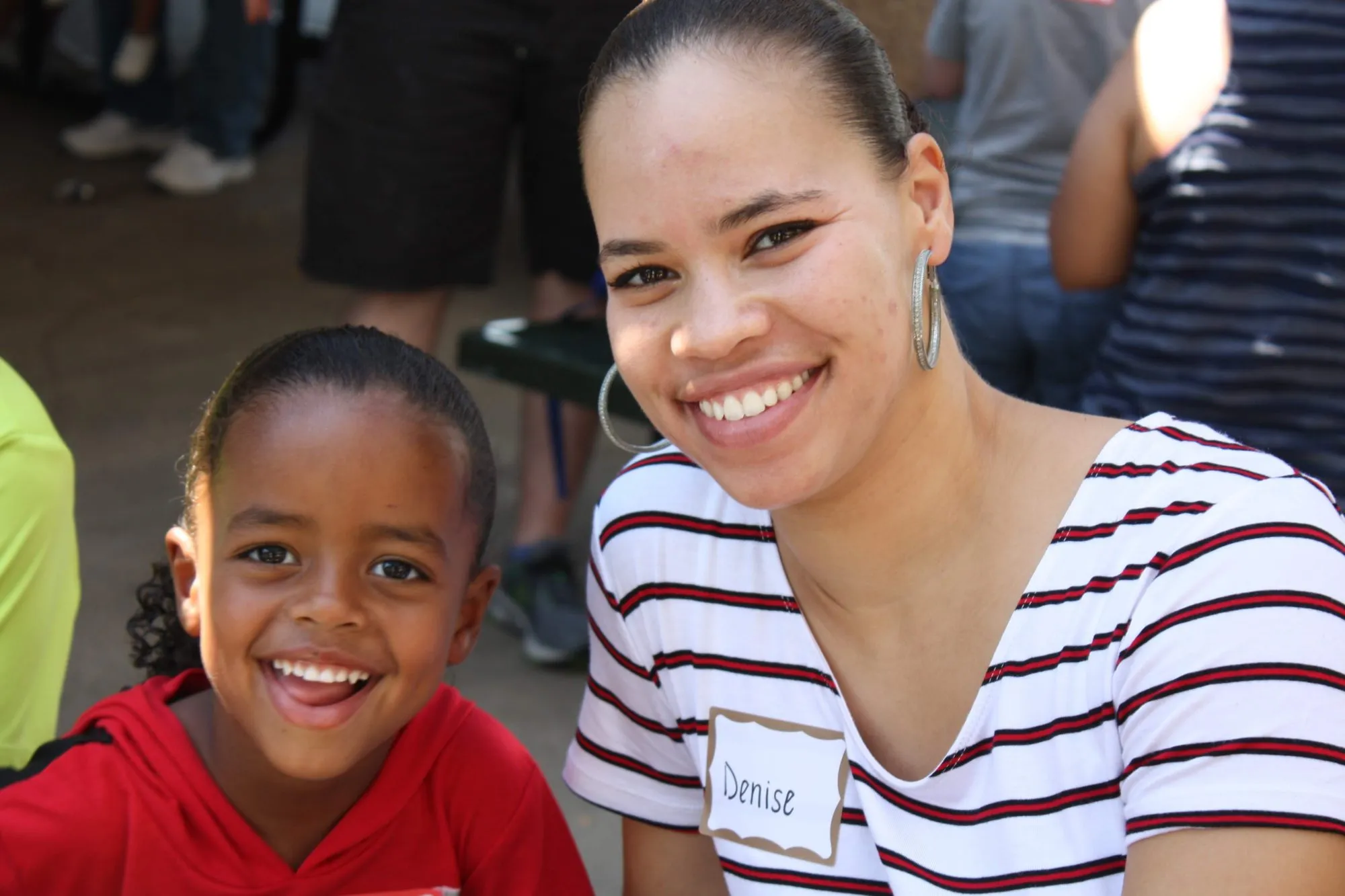A smiling boy poses with a volunteer wearing a name tag