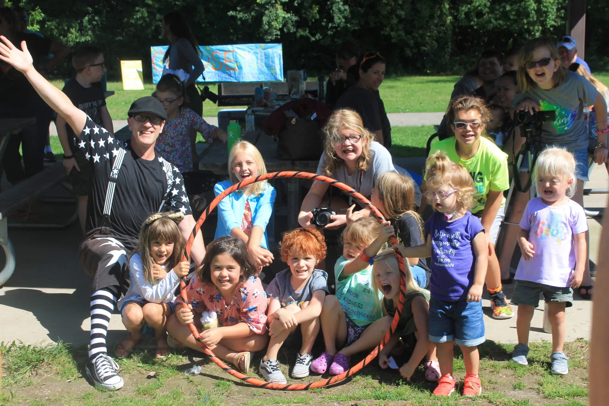 A large group of children and adults pose together outdoors