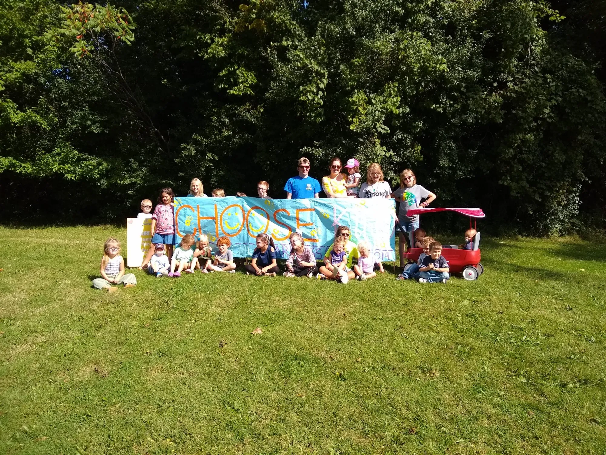 A large group poses together behind an event banner outdoors