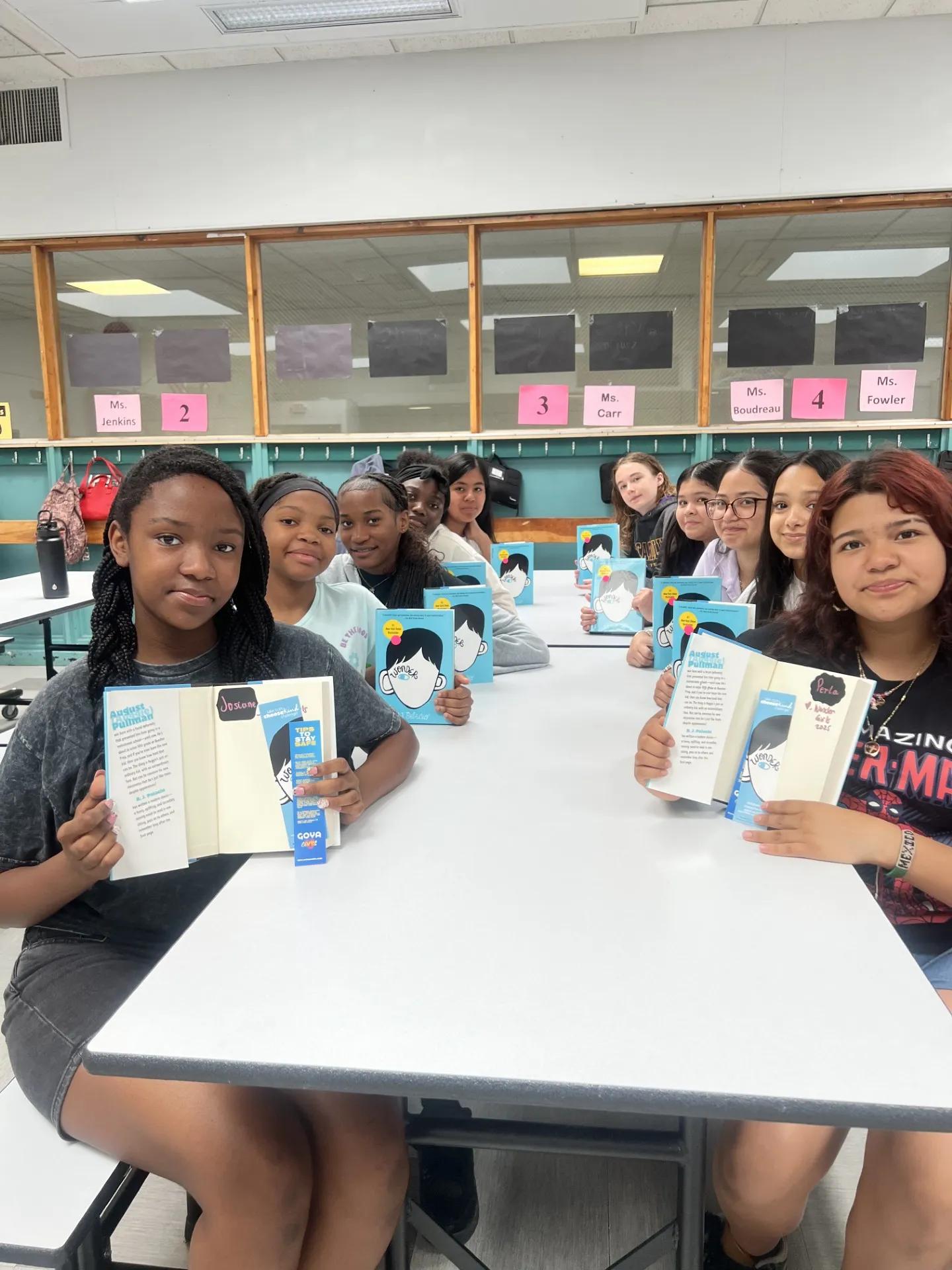 A group of people hold up books from the suggested reading list