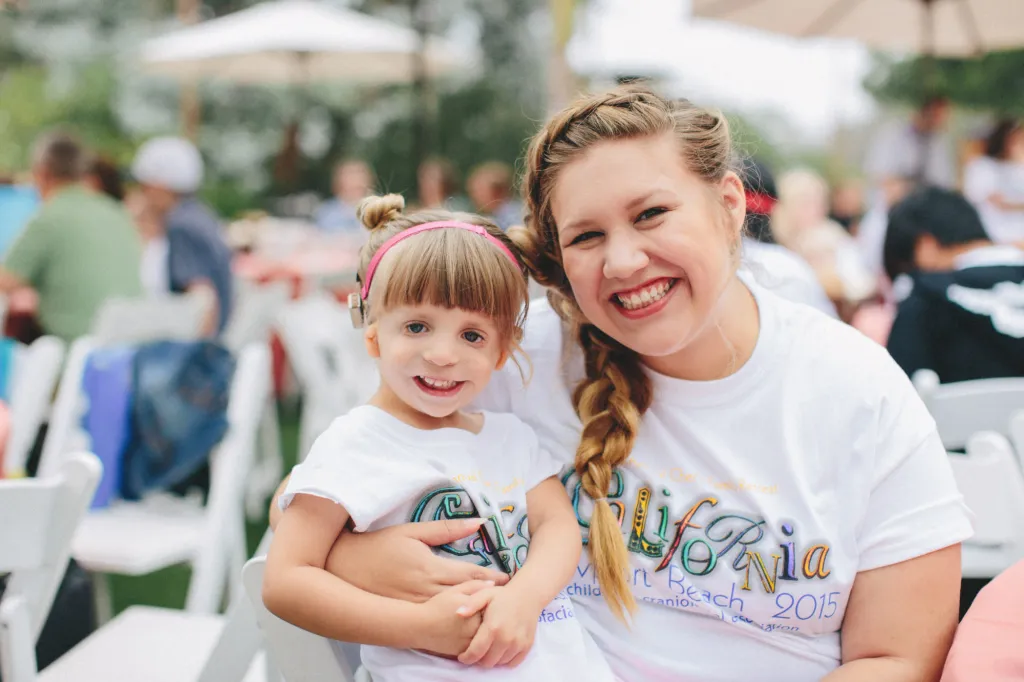 A volunteer and a child smile together at a CCA event