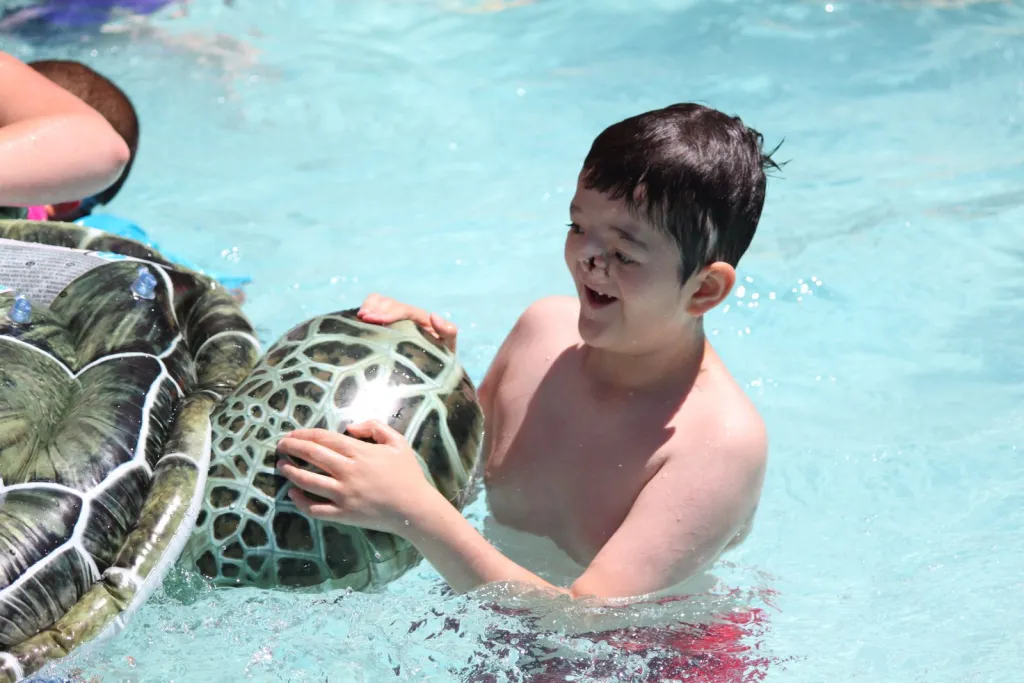 A child holds a toy turtle while playing in the pool