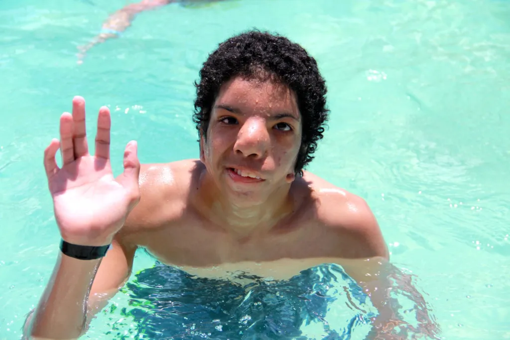 A person raises their hand while swimming in a pool