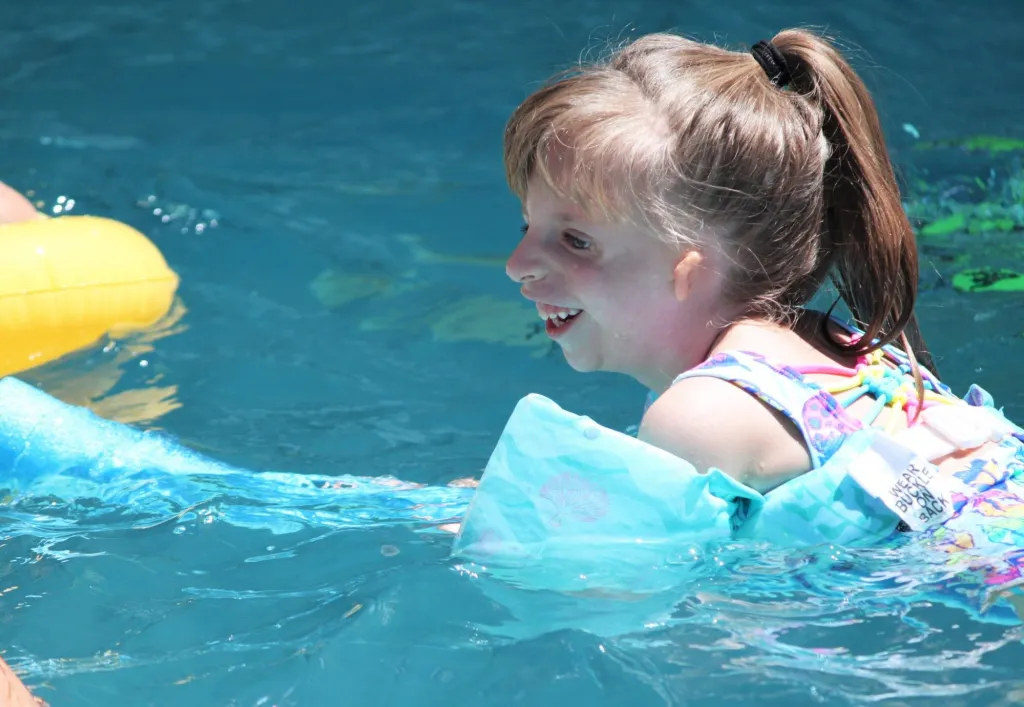 Two children play together with a pool float