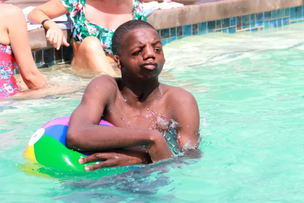 A child holds a pool toy while swimming