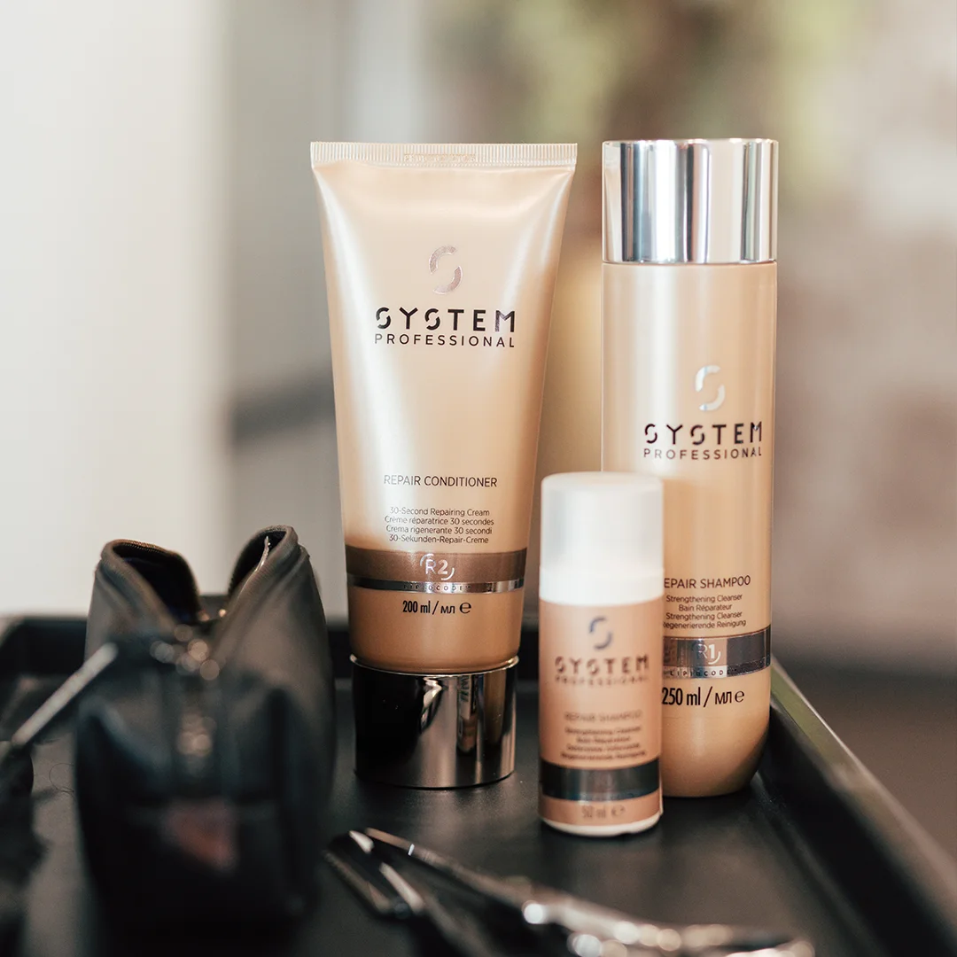 System Professional haarverzorgingsproducten: conditioner, shampoo en serum op zwarte tray naast een etui.