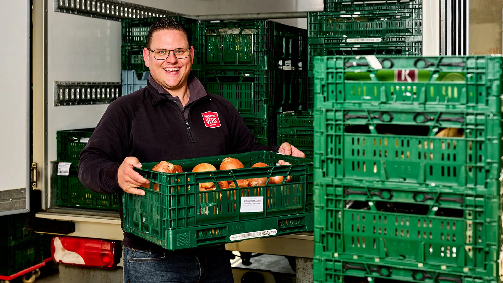 Medewerker van Heerkens Vers met een krat groente in de laadruimte van een bestelwagen