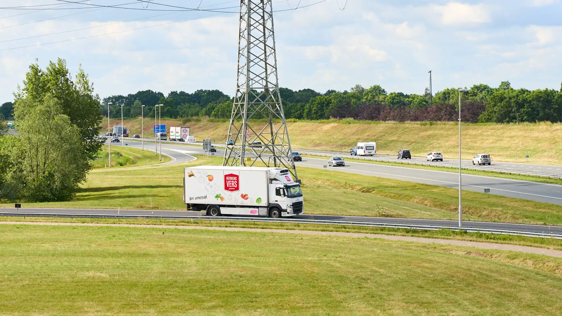 Vrachtwagen van Heerkens Vers op de snelweg tussen weilanden