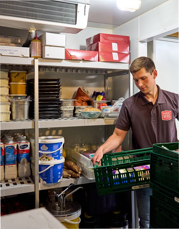 Medewerker van Heerkens Vers zet kratten groente in een voorraadrek