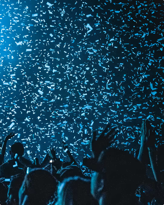 Foule célébrant sous une pluie de confettis bleus lors d'un concert ou d'une fête.