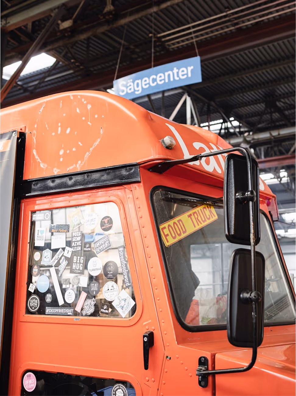 Camion alimentaire orange avec fenêtre couverte d'autocollants et panneau FOOD TRUCK.