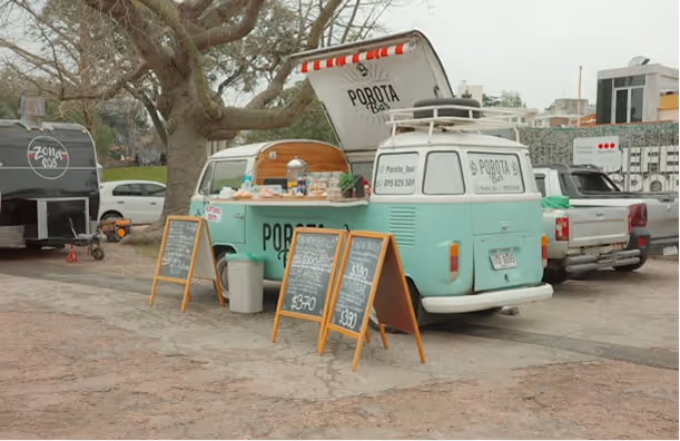 Camionnette vintage bleu clair convertie en food truck avec menus sur tableaux noirs devant.