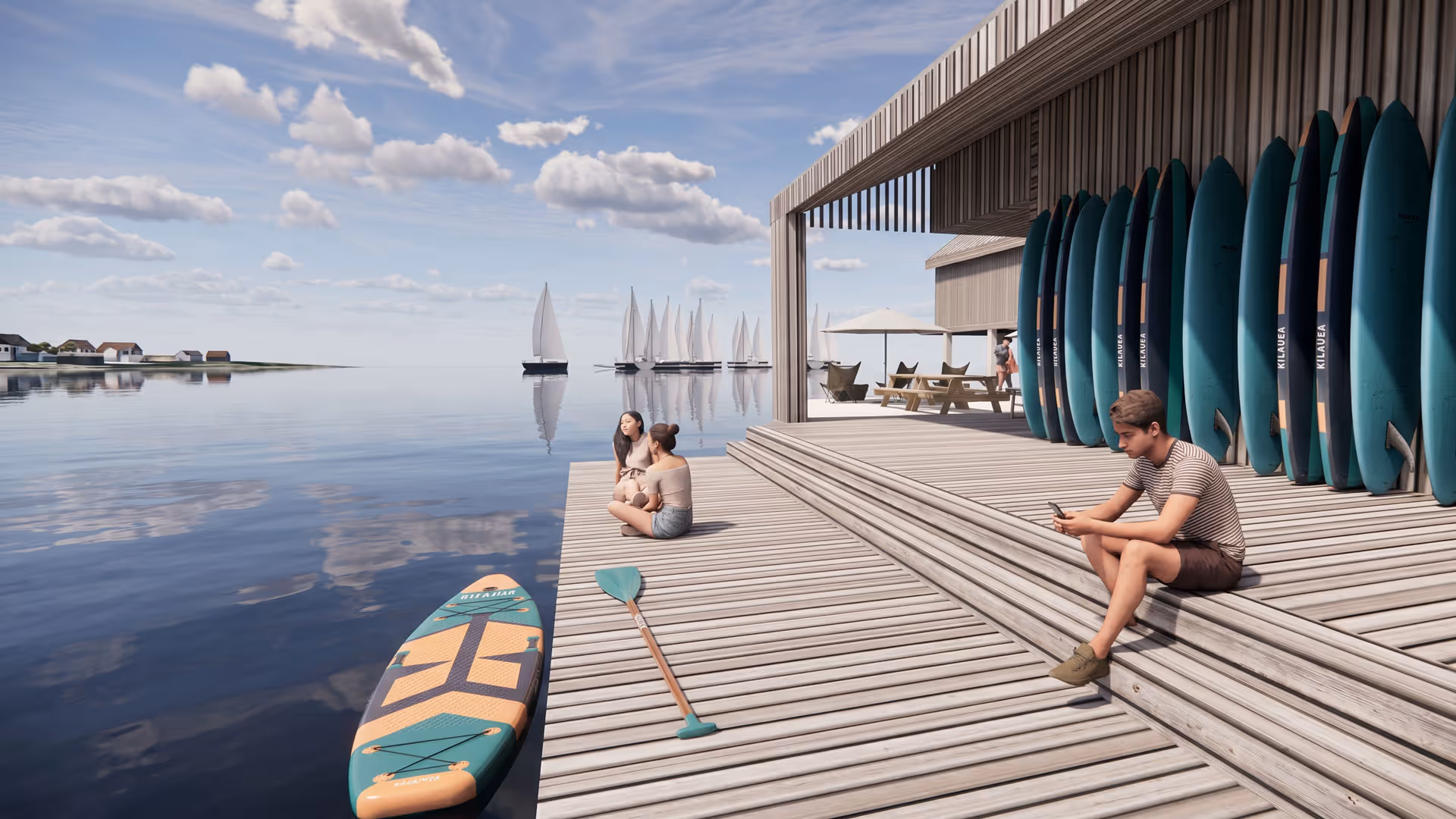 Een jonge man zit op houten traptreden bij het water, omringd door opgestelde surfplanken, terwijl twee vrouwen aan het waterrand zitten en verderop zeilboten op een kalme zee varen.