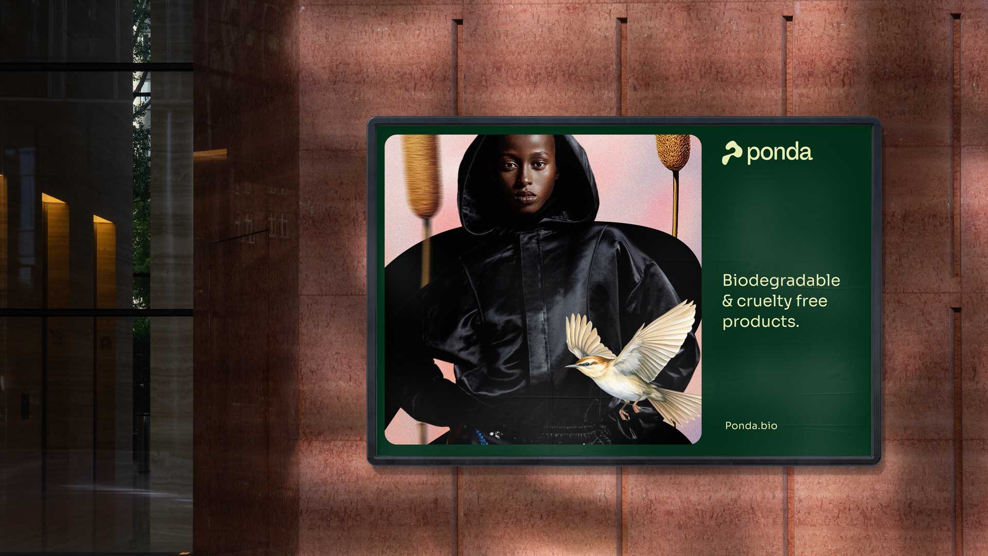 Billboard ad with model in black hooded jacket, bird, and text promoting biodegradable cruelty-free products using biopuff technology