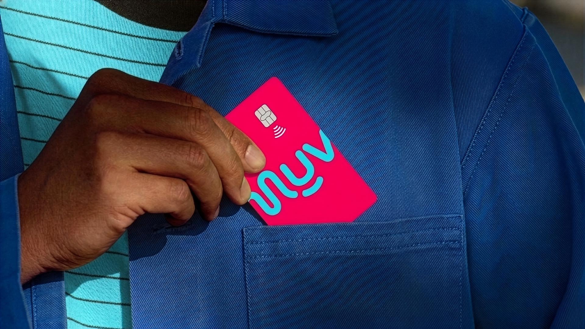 Person inserting the bright pink Metromuv card with turquoise text into a blue jacket pocket.