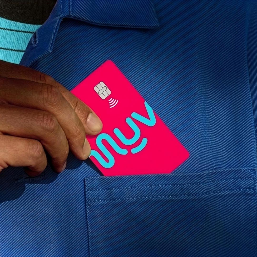 Hand placing a bright pink card with blue letters into a blue shirt pocket.