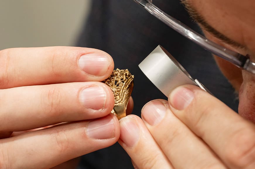 gold ring being inspected with loupe