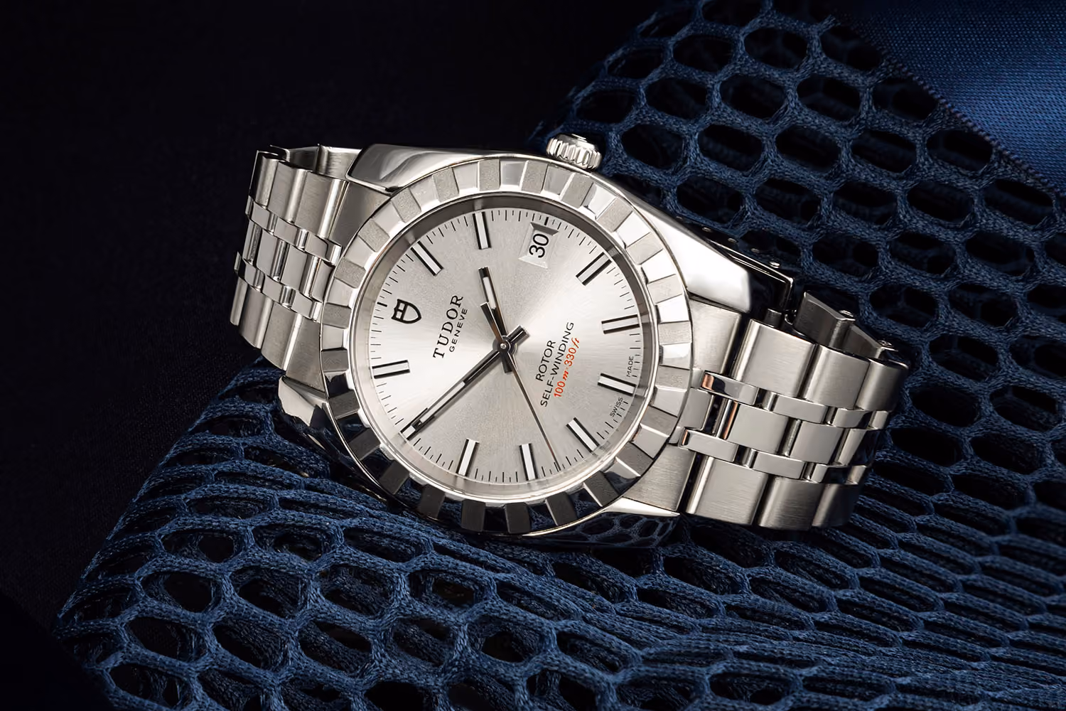 steel Tudor self-winding watch with date on blue mesh fabric background.