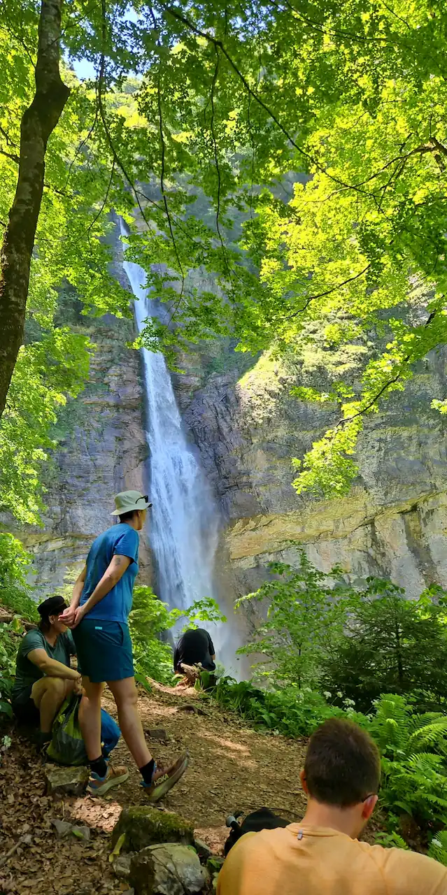People in the rainforest Perucica and waterfall Skakavac in the background
