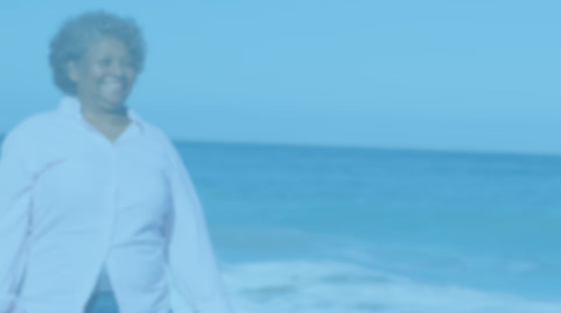 Blurry image of a person smiling on a beach with ocean waves in the background.
