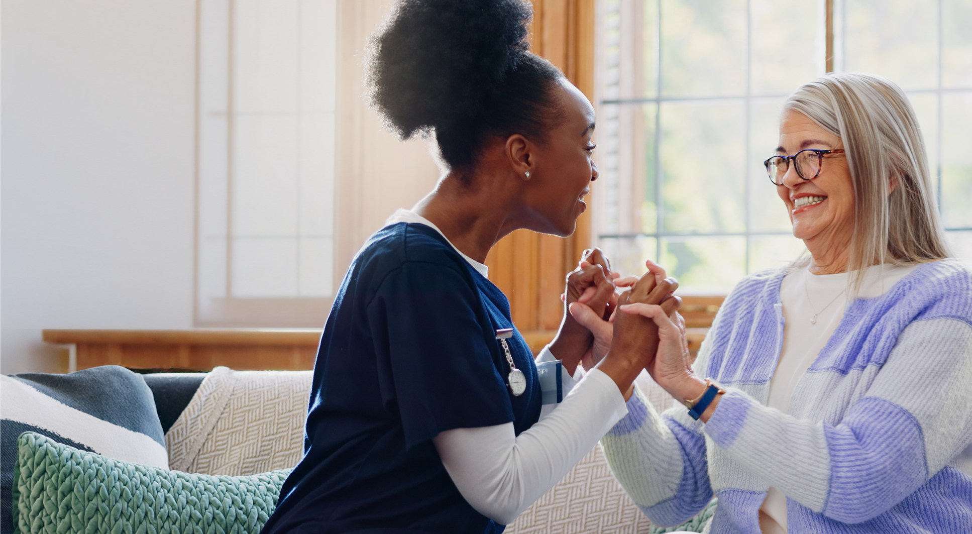 A care team member sitting with and holding hands with a patient