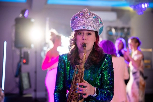 saxophonique at a wedding, looking directly at the camera