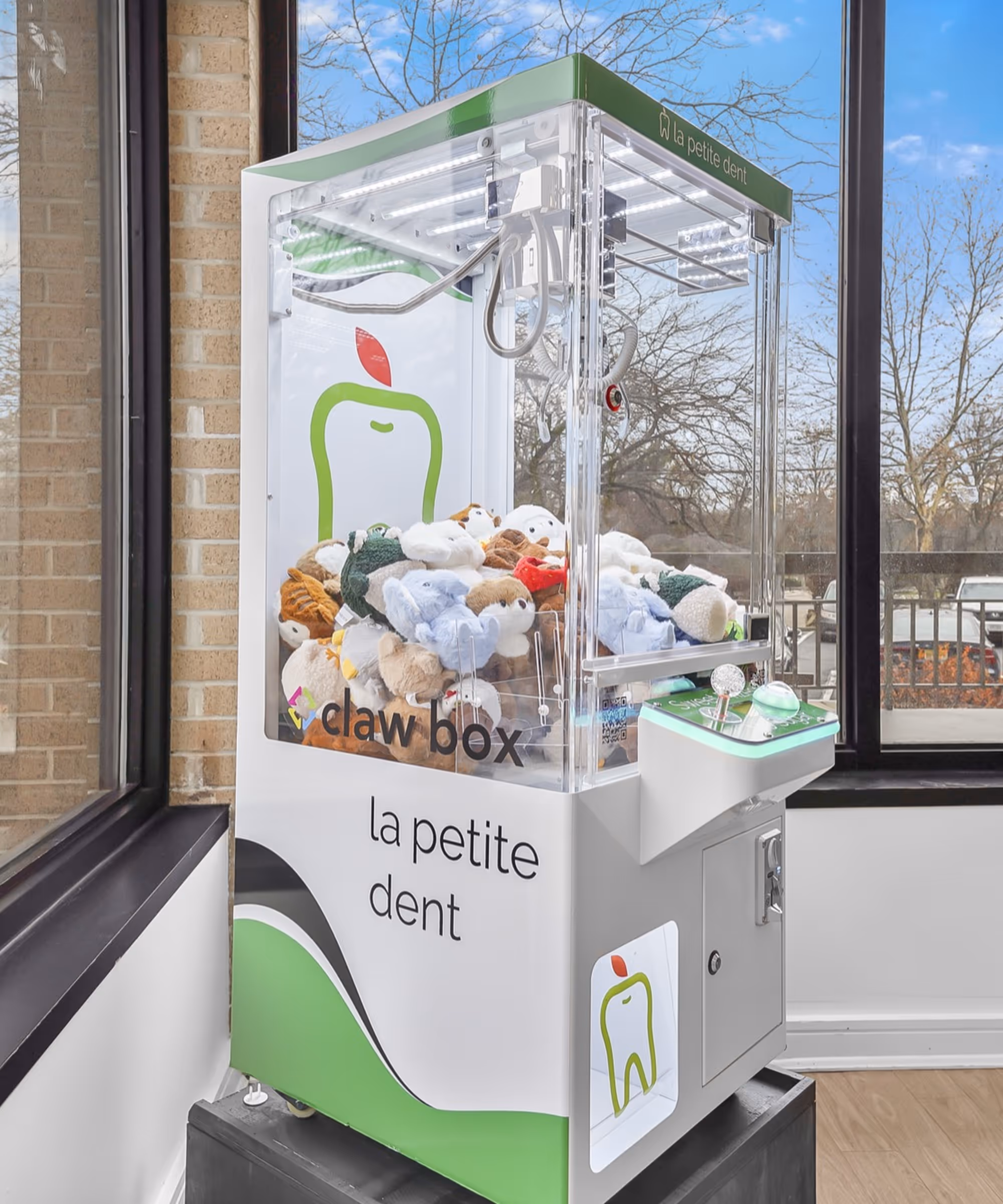 Mini claw box machine at La Petite Dent pediatric dental waiting room with co-branded green and white wrap