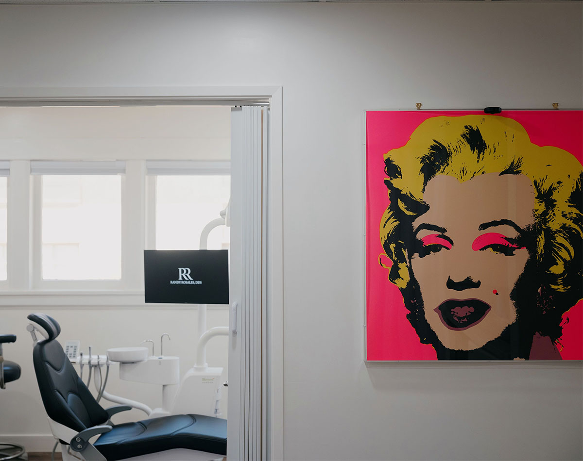 Modern dental office with black chair and pop art poster of Marilyn Monroe on white wall.