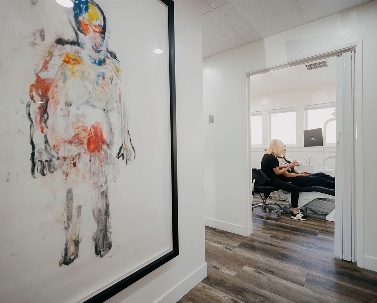 Person receiving care from another seated in a modern room with abstract artwork on the wall.