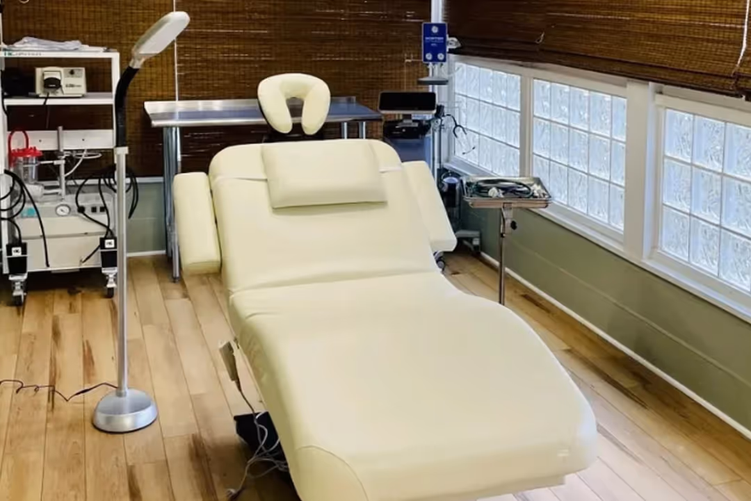 Modern medical or spa exam room with an adjustable beige treatment chair and equipment.