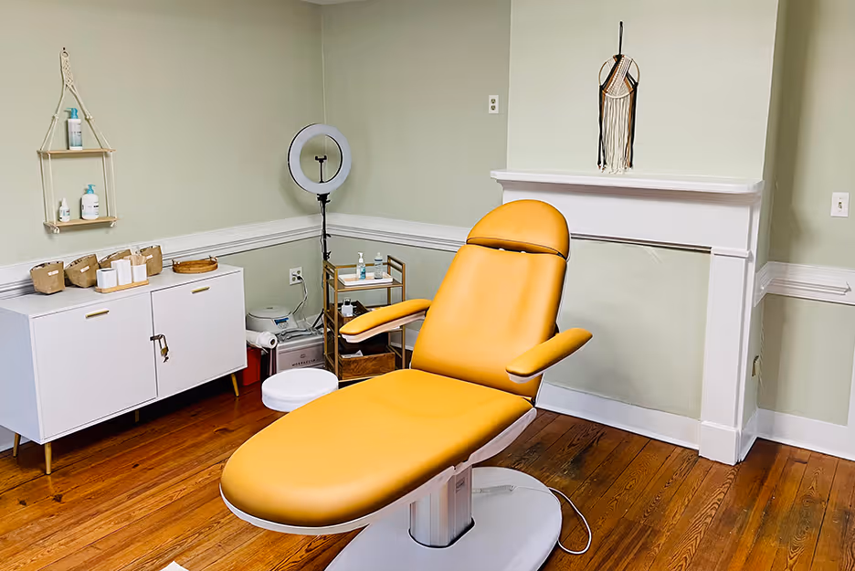 Yellow reclining chair in a clean treatment room with white cabinets and wooden floors.
