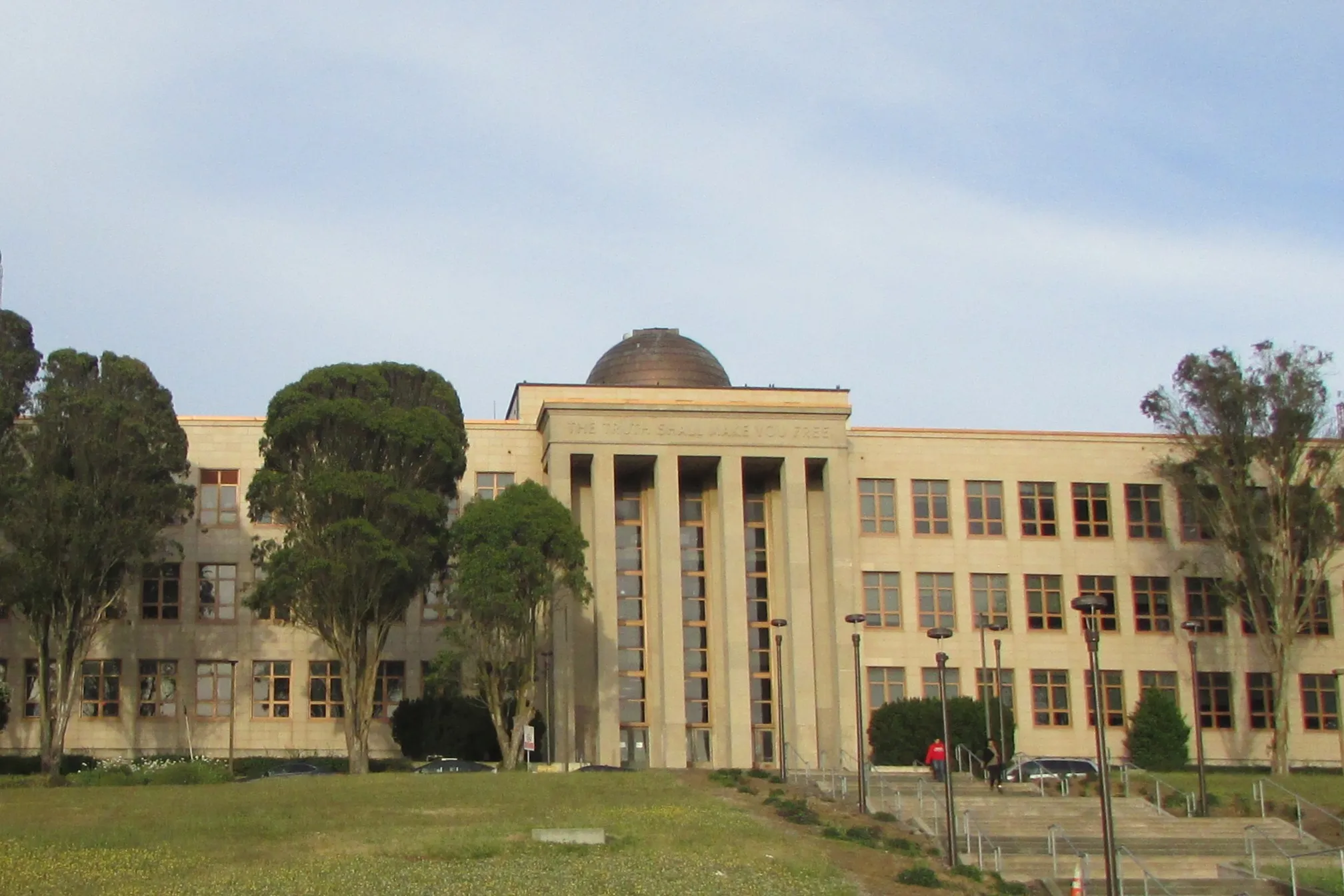 City College building with a copper observatory dome rising above the entrance, surrounded by tall trees and open sky, symbolizing perspective and discovery.