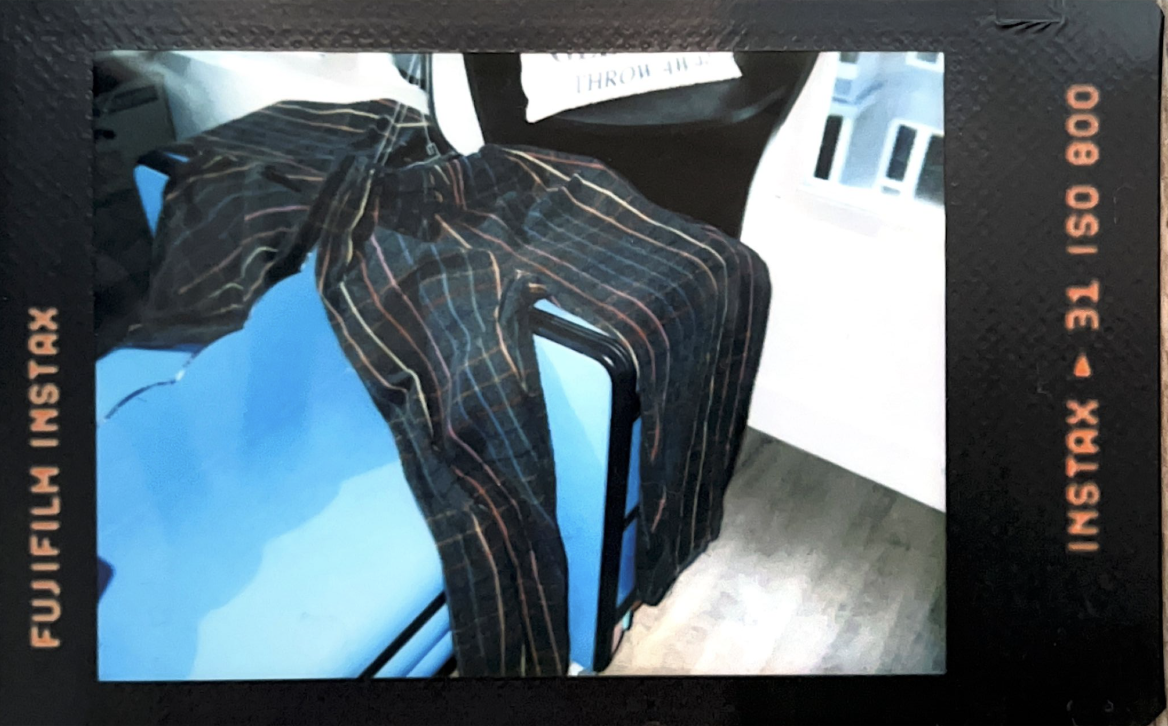 A photo taken with a flash on an instant film camera. The flash has caused it to be overexposed. The photo features black pants with rainbow stripes.