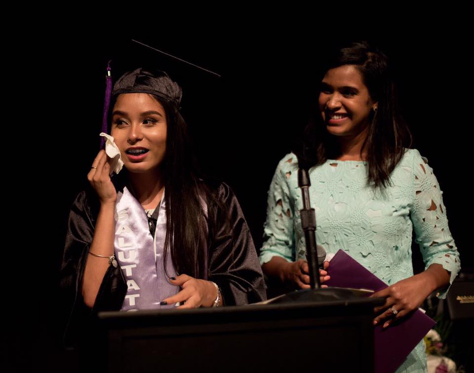 Graduate in cap and gown speaks emotionally at podium during ceremony