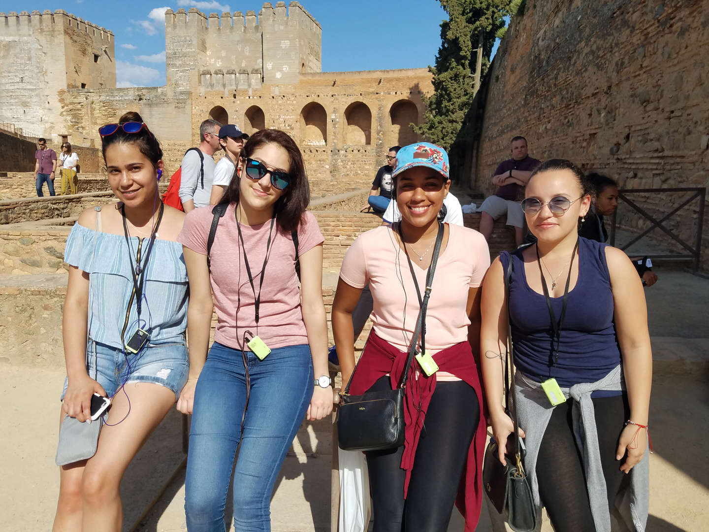 Four students with lanyards posing together at historic castle ruins