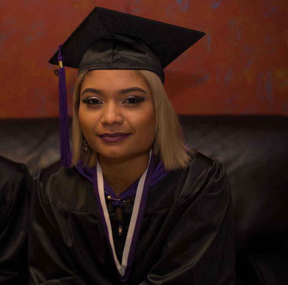 Graduate wearing black cap and gown with purple tassel
