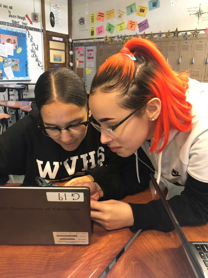 Two high school students collaborating on a laptop in classroom