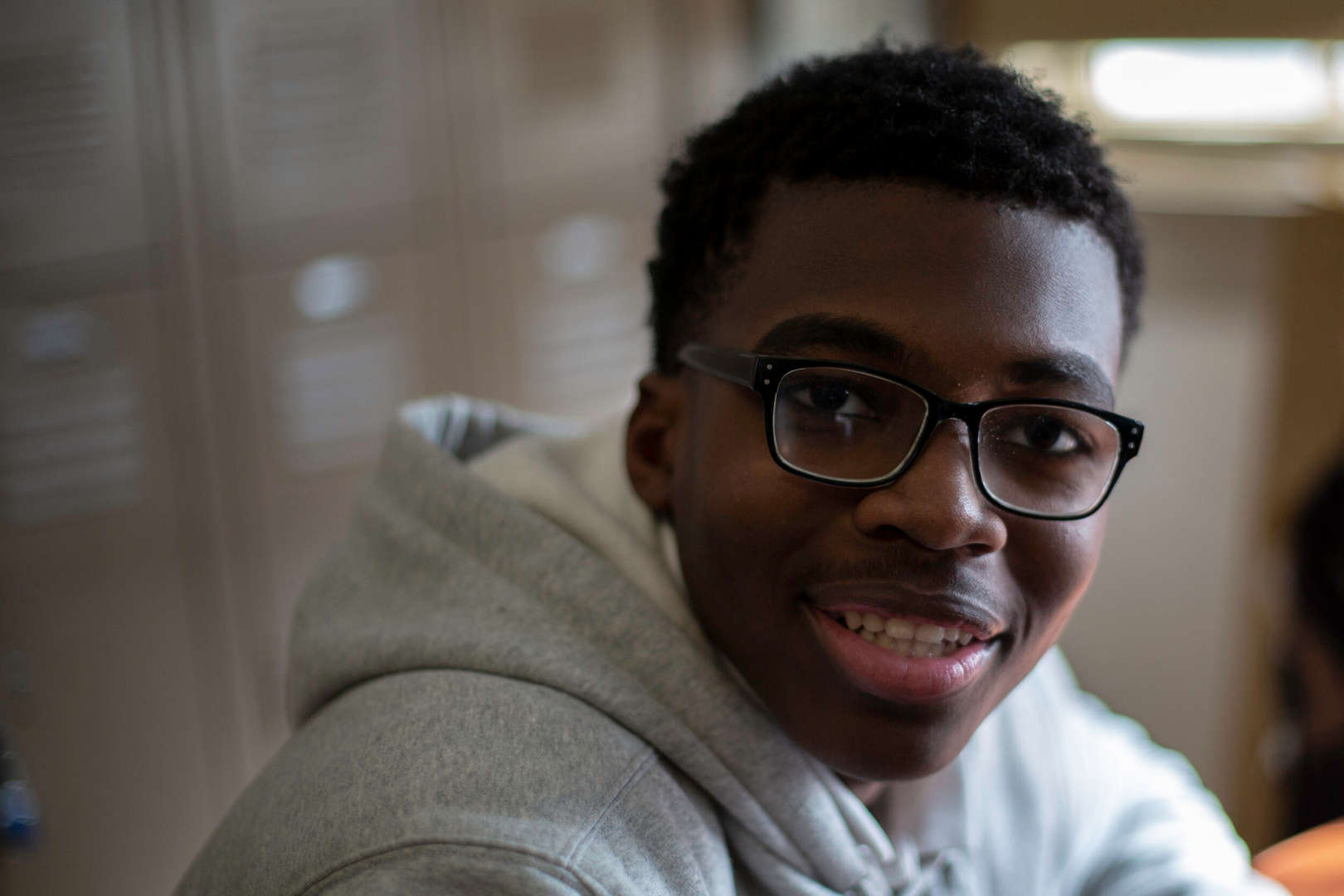 Smiling student wearing glasses in a school hallway