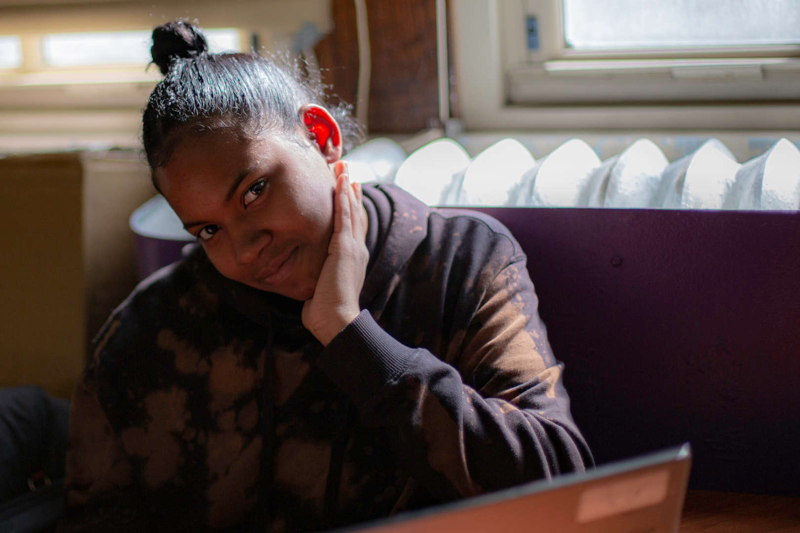 Student wearing a hearing aid smiles while working on a laptop